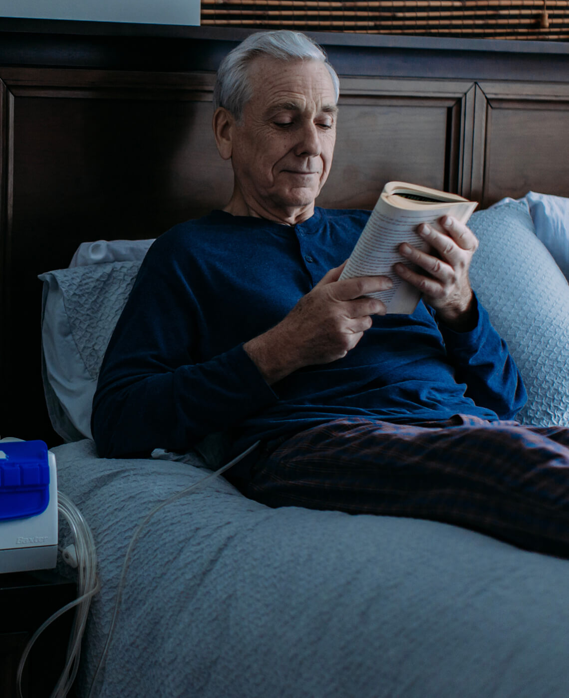 Man reading a book in bed with a catheter